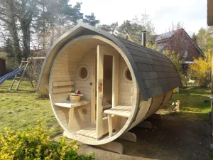maßgefertigte Gartensauna, Ansicht von vorne, zwei Rundfenster Bullauge, kleine Terasse mit zwei Sitzmöglichkeiten